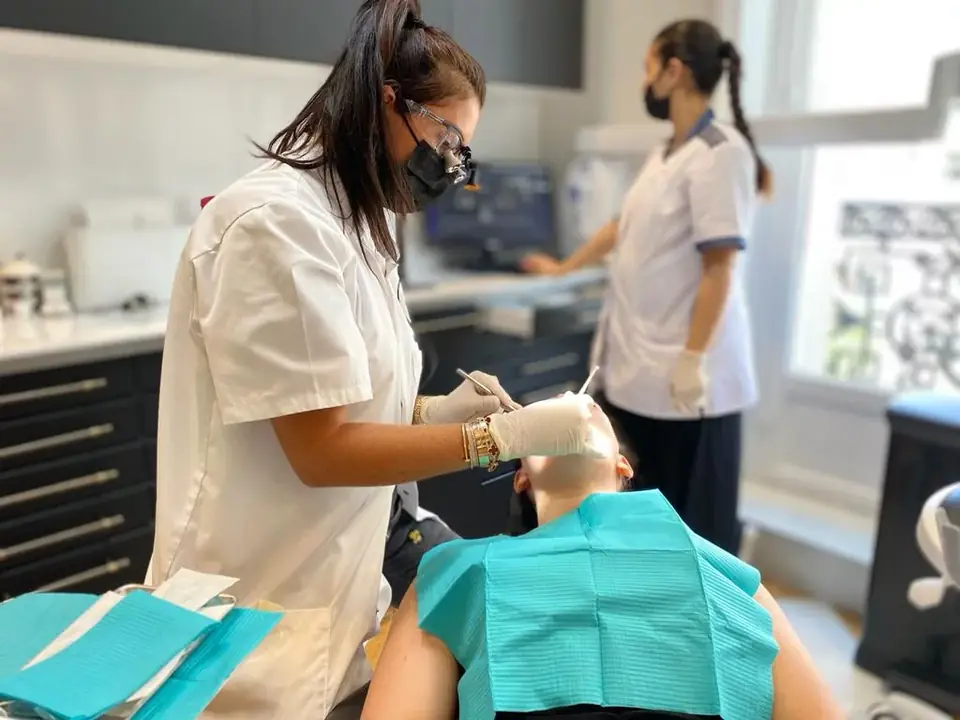 Treatment under way in the chair: magnifying loupes and surgical mask, Paris 8 practice